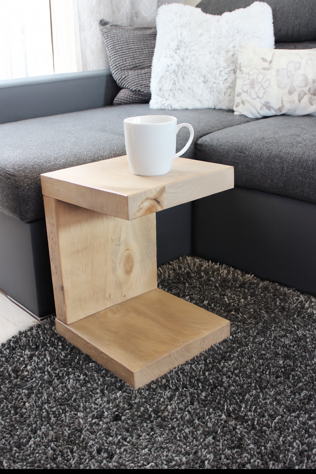 Wooden side table with a white mug on a gray sofa