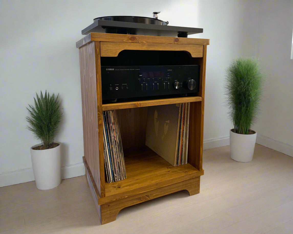 Wooden audio equipment cabinet with turntable, receiver, and records on a white floor with plants.