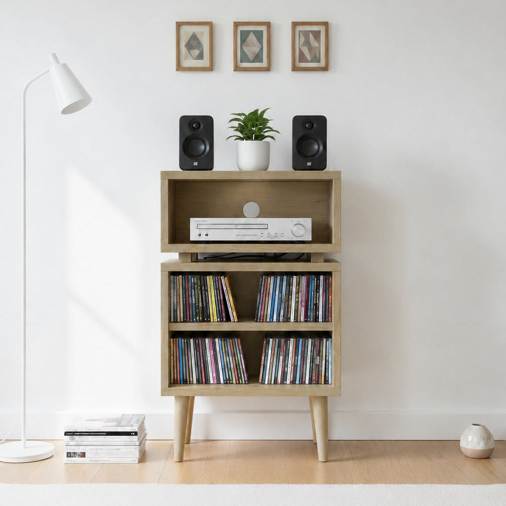 A light wood media console with three tiers and tapered legs, styled with speakers, a small plant, a DVD player, and records, set against a white wall in a minimalist room.
